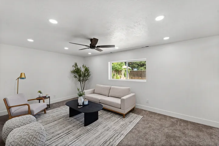 Recessed lighting, ceiling fan, white walls, carpeted flooring, and a large window