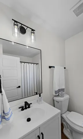 White vanity with integrated sink, matte black faucet, and framed mirror