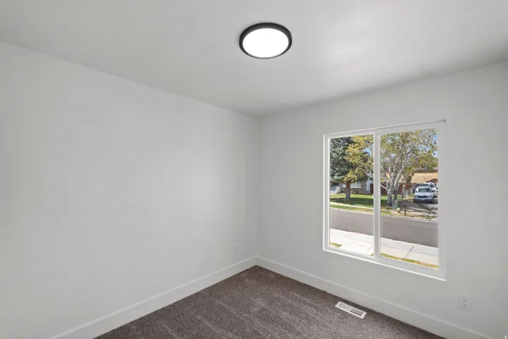 Neutral wall finishes, a large window, and a flush-mount ceiling fixture