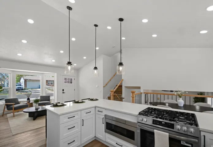 Open-concept kitchen with white cabinetry and a built-in stainless steel oven