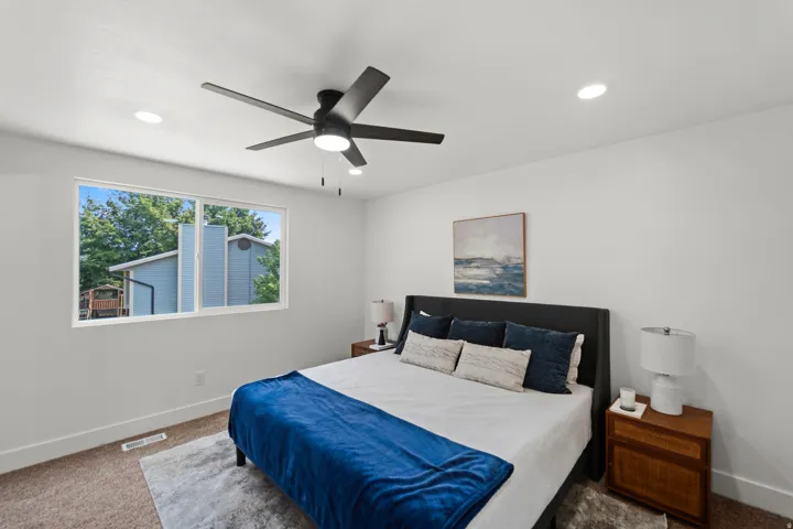 Recessed ceiling lighting, ceiling fan, white walls, and a large window