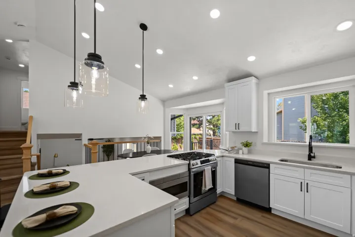 Kitchen featuring white cabinetry, stainless steel appliances, white countertops, wood-finish flooring, and recessed lighting