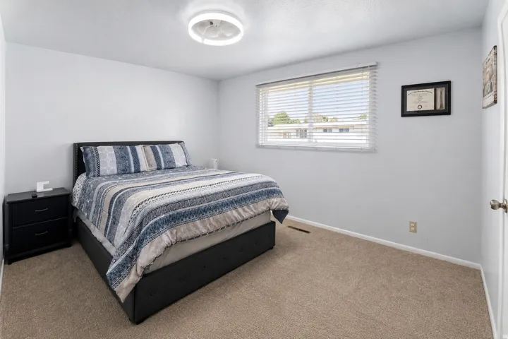 Carpeted flooring, white walls, and a window with blinds