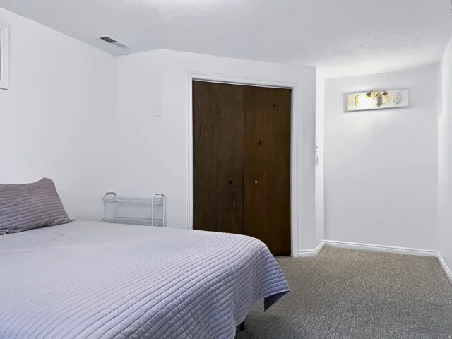 Bright bedroom with neutral walls, carpeted flooring, and recessed ceiling lighting