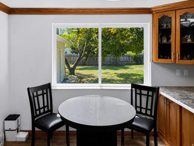 Bright breakfast nook flooded with natural light through expansive dual-pane windows overlooking manicured grounds and mature landscaping