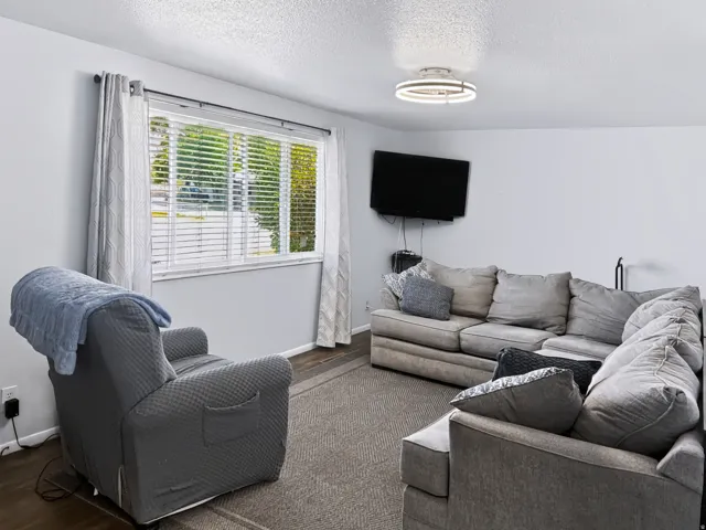 Recessed window with blinds, overhead light fixture, and wood-finish flooring