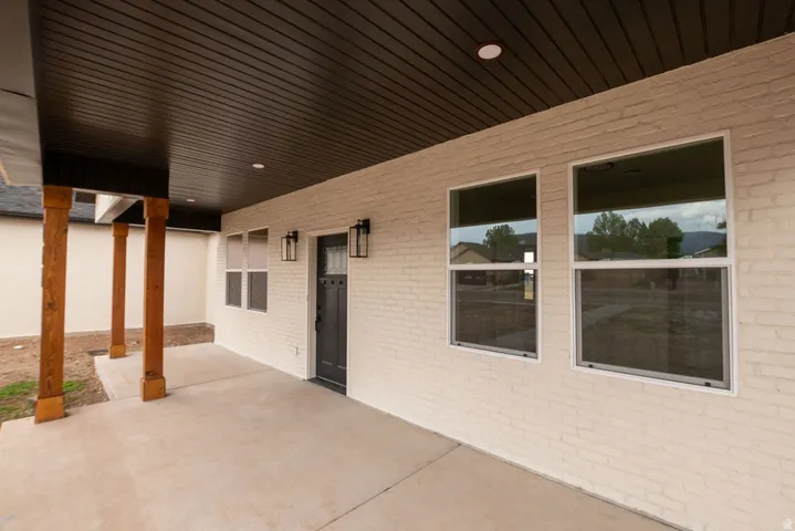 Covered patio with a concrete surface, wooden support pillars, and recessed lighting