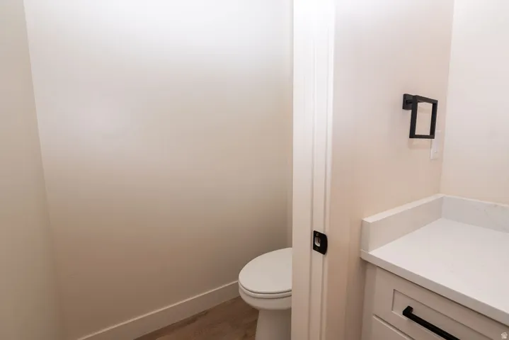 White solid surface countertop, white cabinetry with matte black hardware, and wood-finish flooring