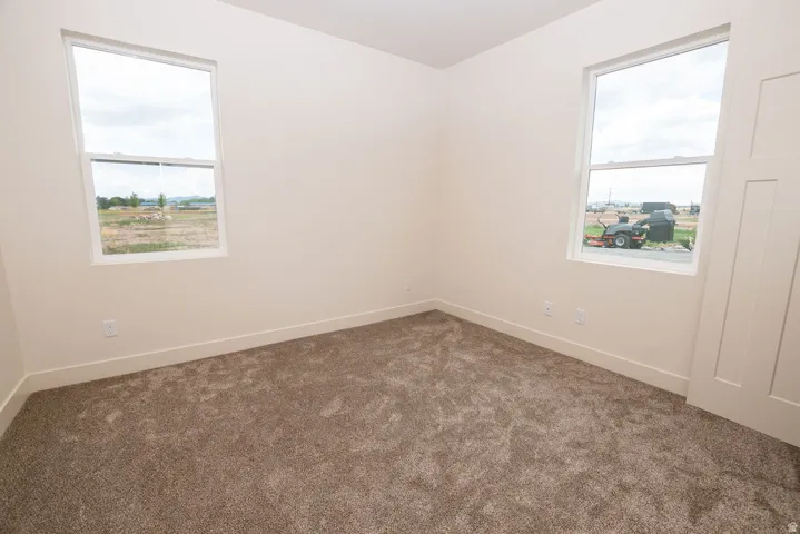 Neutral-toned walls, plush carpeting, dual windows, and a panel-style door
