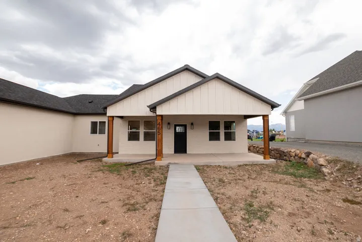 Contemporary exterior with a covered front porch, wood-finish columns, dark asphalt shingle roof, and a concrete walkway