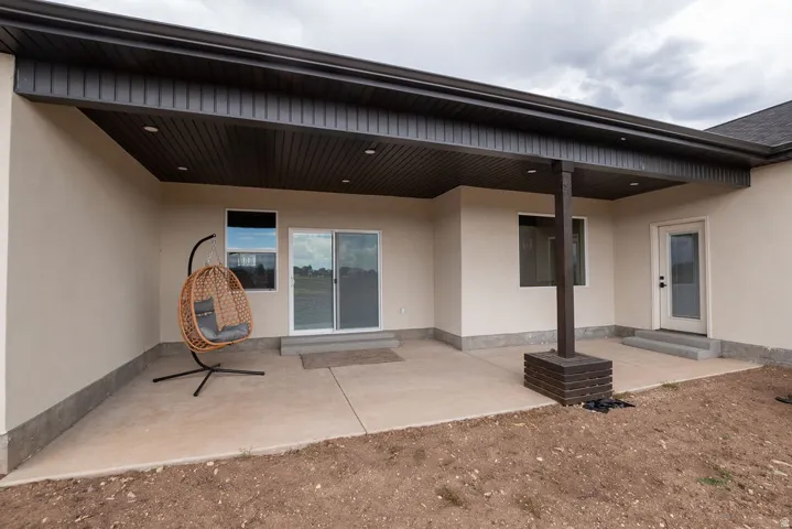 Covered concrete patio with recessed lighting, a sliding glass door, an exterior entry door, and a support column with a brick base