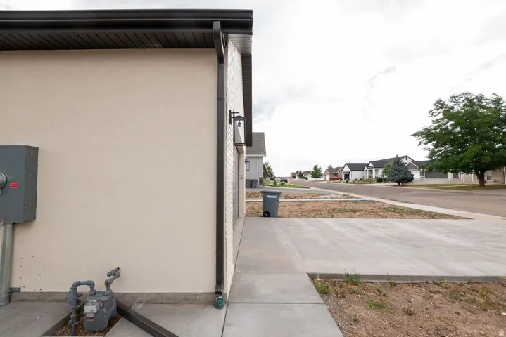 Stucco exterior with dark gutters and a concrete walkway