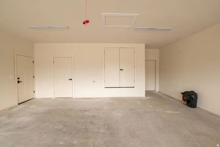 Spacious garage featuring a concrete floor, multiple access doors, and overhead lighting