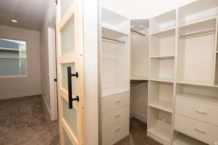 Custom closet system with white shelving, integrated drawers, and hanging rods