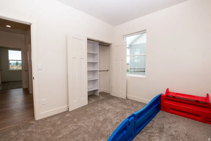 Carpeted room with a built-in closet featuring shelving and a window