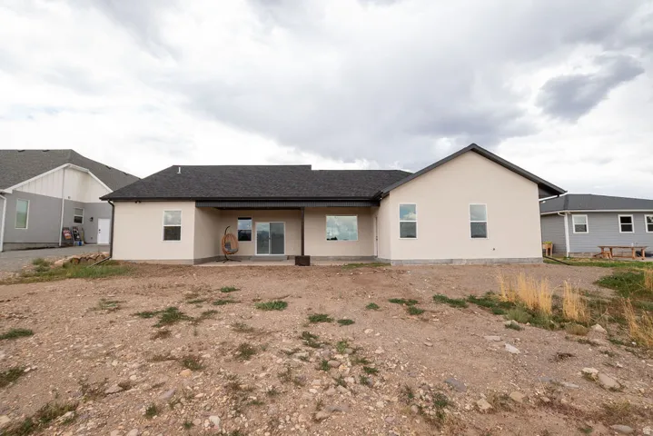 Rear exterior featuring a covered patio, multiple windows, and sliding glass doors