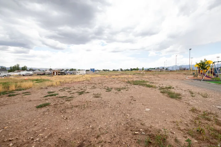 Expansive undeveloped land featuring a gravel and dirt surface, with scattered dry vegetation
