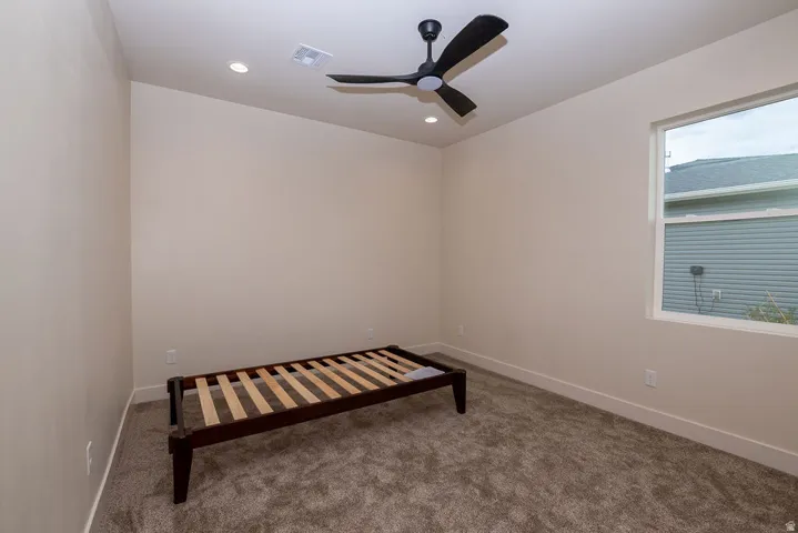 Textured carpeting, recessed lighting, and a contemporary ceiling fan
