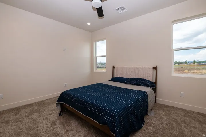 Room featuring neutral wall tones, carpeted flooring, two windows, recessed lighting, and a ceiling fan