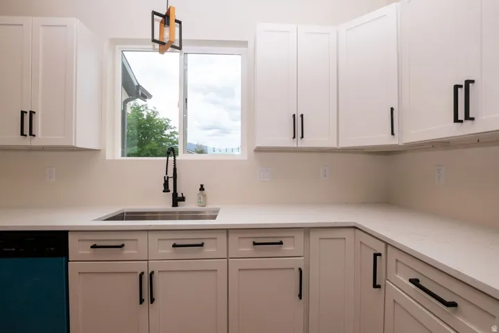 White shaker-style cabinetry with black hardware, white countertops, built-in stainless steel sink, and black gooseneck faucet