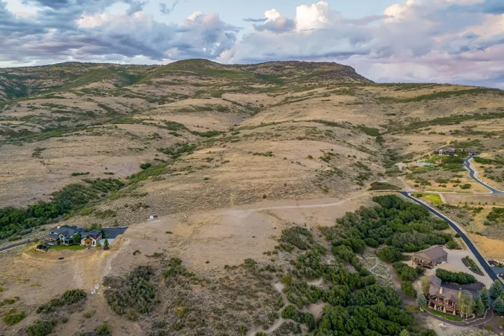 Expansive land featuring a mountainous backdrop, natural vegetation, and paved roads