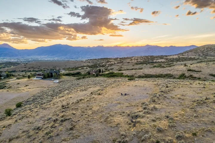 Expansive land with distant mountain ranges and scattered residential structures