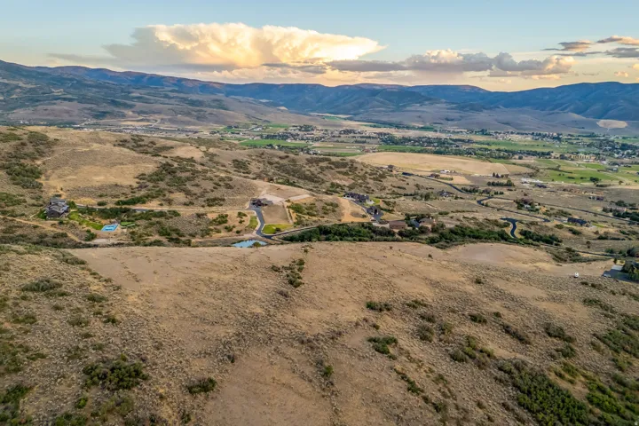Expansive undeveloped land with a winding road leading to a residential structure