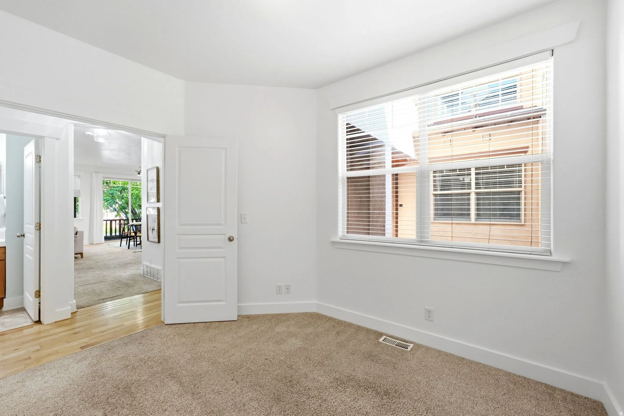 Carpeted flooring, white walls, white trim, window with blinds, and white interior doors