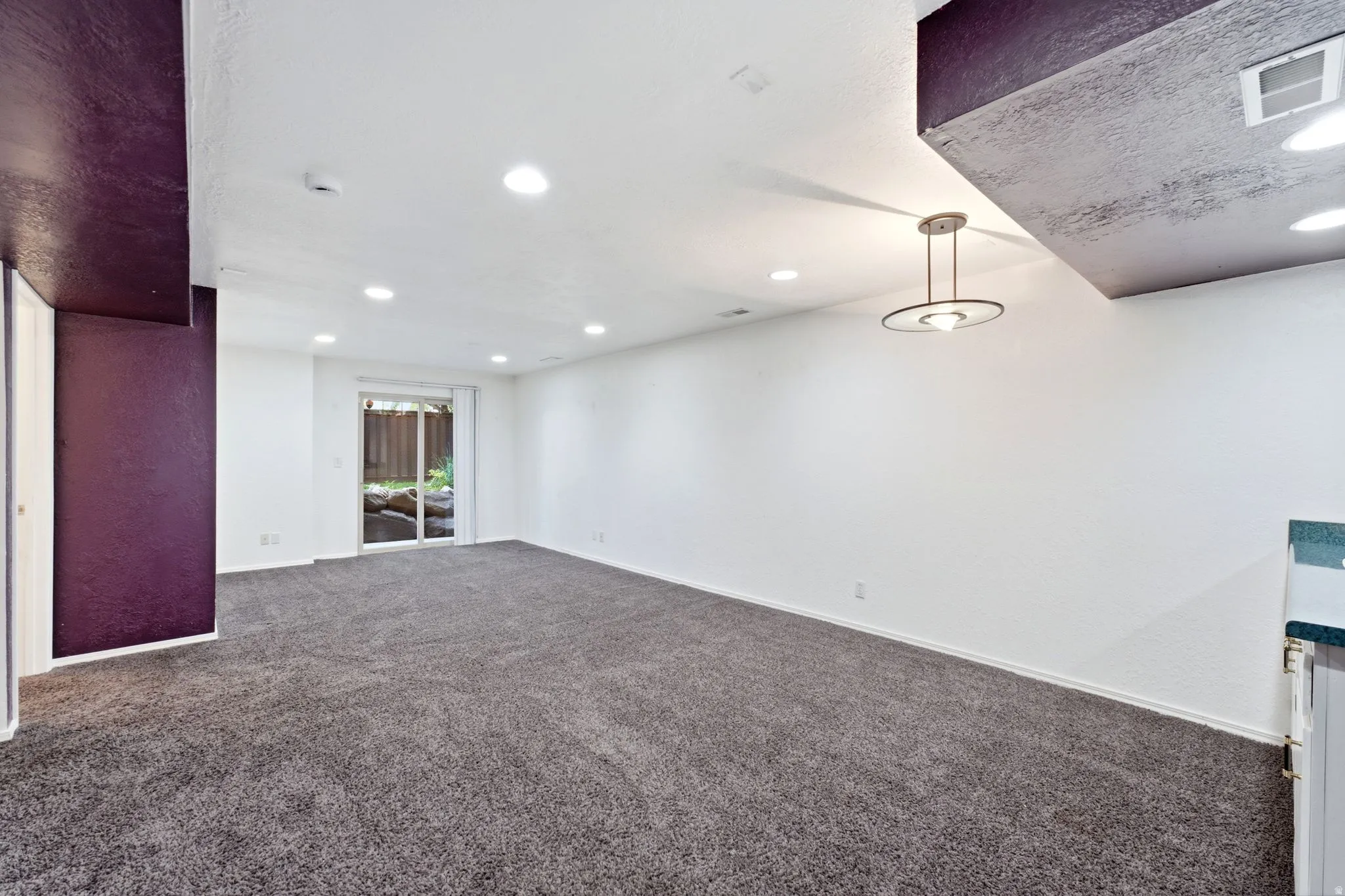 Recessed lighting, sliding glass door, overhead light fixture, light gray carpeting, and a built-in countertop