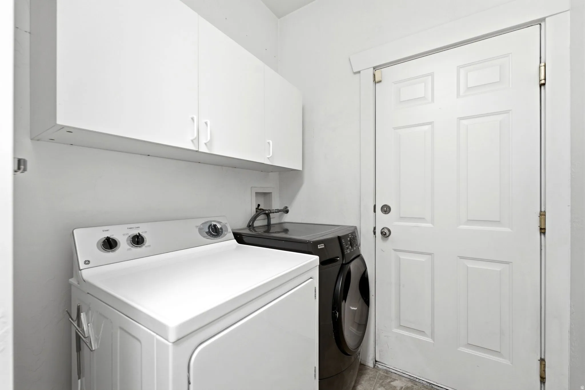 Laundry area featuring white cabinetry and a paneled door