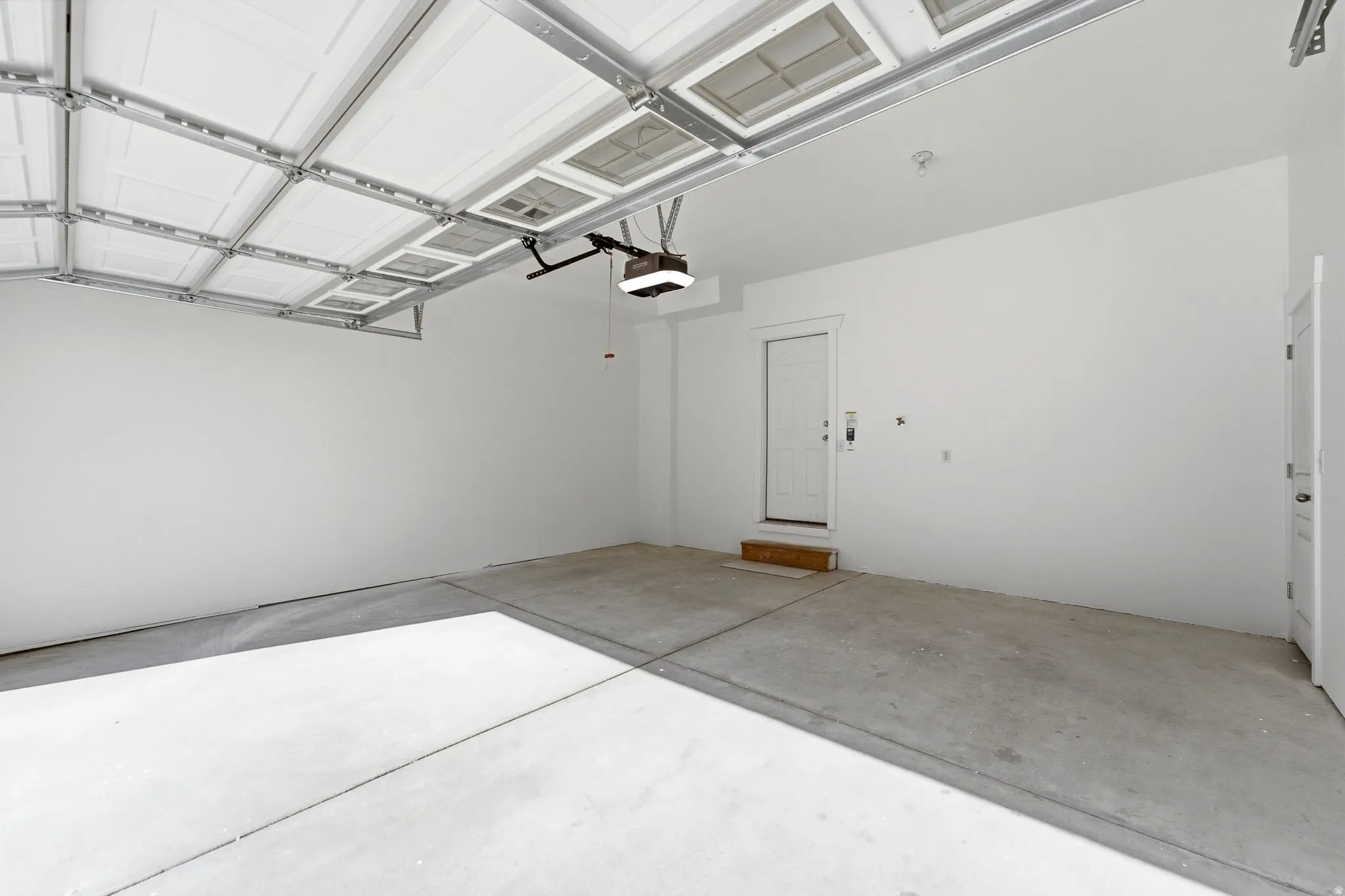 Spacious garage with a concrete floor, white walls, and an automatic overhead door