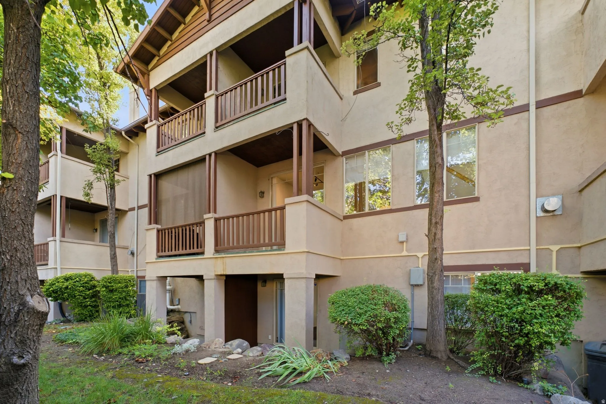 Multi-story building exterior with stucco finish and wood-finish trim