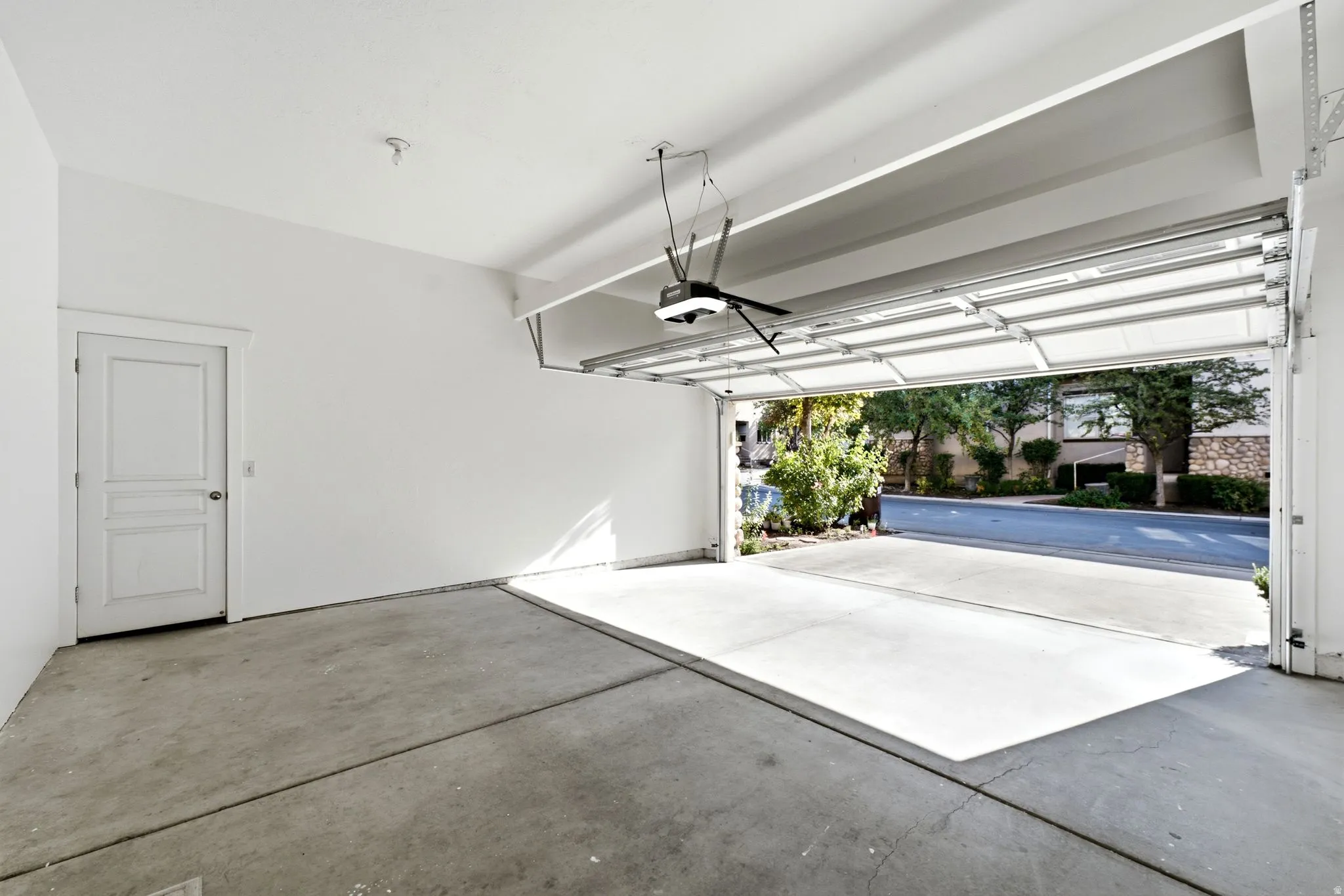 Attached garage with concrete flooring, white painted walls, and an overhead door opener