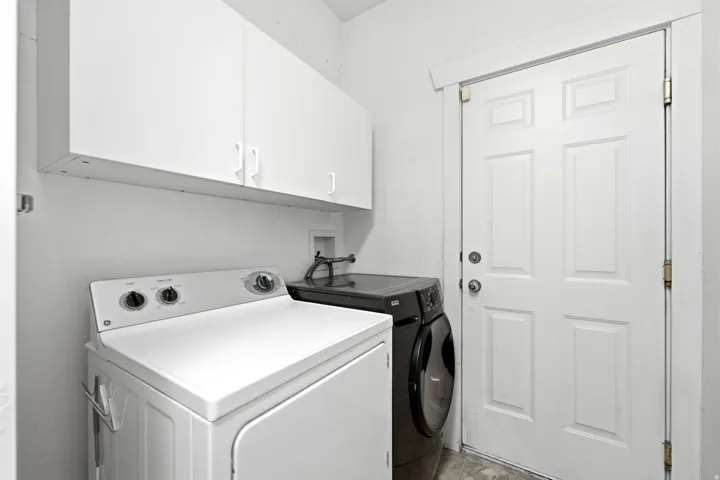 Laundry area featuring white cabinetry and a paneled door