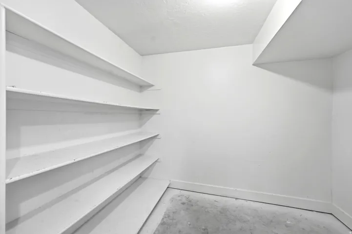 Built-in shelving with multiple storage levels, a light-colored ceiling, and concrete flooring