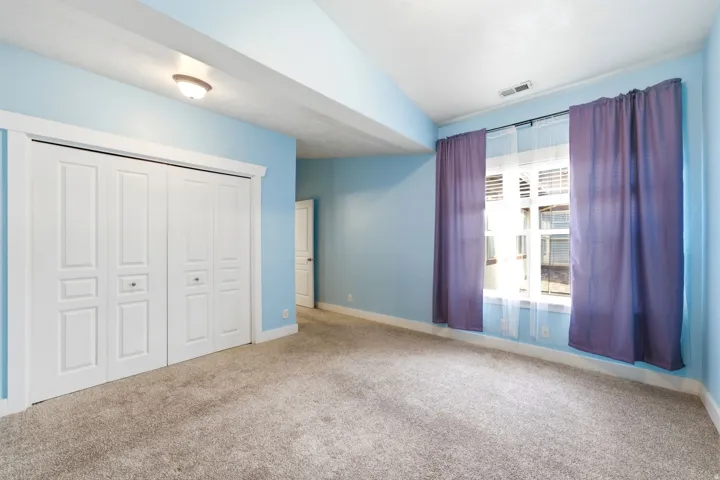Plush carpet flooring, recessed ceiling light, double bi-fold closet doors, and window with white trim