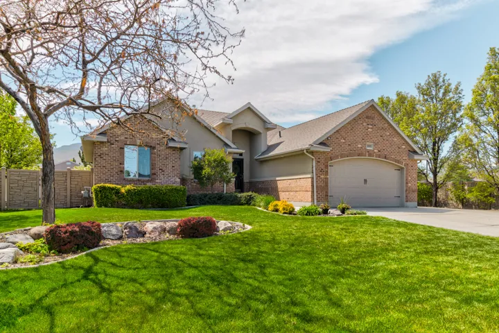 Brick and stucco exterior featuring an arched entryway and an attached two-car garage