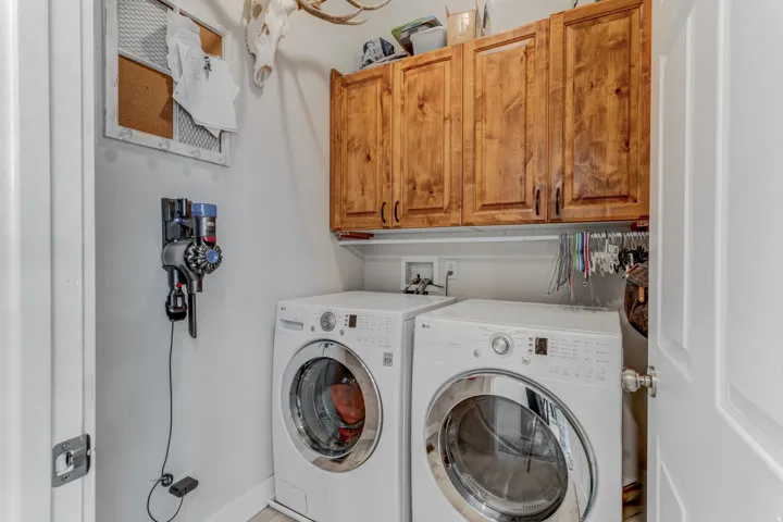 Laundry area featuring upper wood cabinetry and a clothes hanging rod