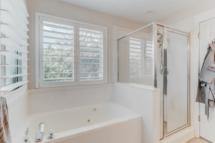 Soaking tub with chrome fixtures, framed by plantation shutters