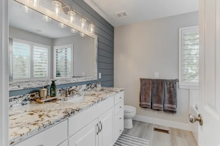 Spacious vanity featuring a white shaker-style cabinet, granite countertop with an undermount sink, and brushed nickel faucet