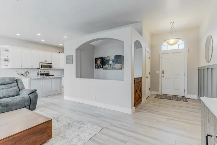 Entryway featuring a paneled door with an arched transom window, a hanging pendant light, and light wood-finish flooring