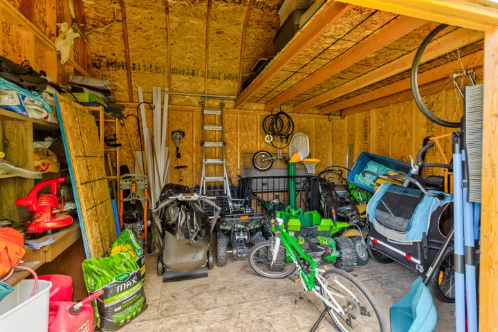 Spacious storage shed featuring oriented strand board walls and ceiling, exposed wood framing, and built-in shelving