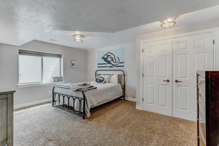 Carpeted room featuring a window with blinds, light gray walls, white baseboards, and two semi-flush mount ceiling lights