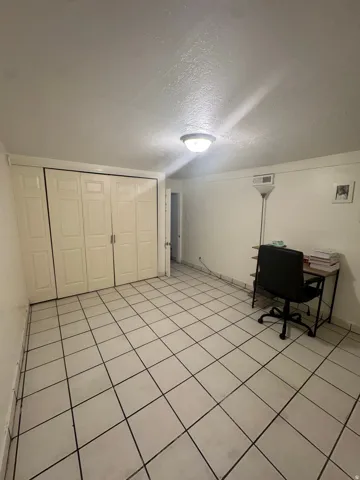 White tiled flooring with dark grout, featuring a built-in closet with bifold doors and a ceiling-mounted light fixture