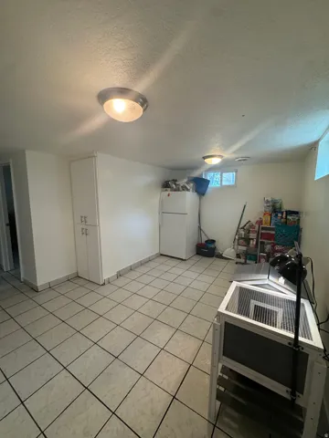 Recessed lighting illuminates the space with tile flooring, white painted walls, and a white baseboard