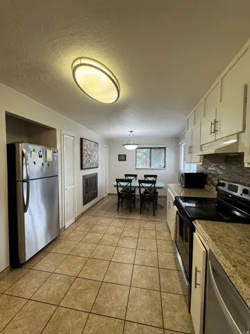 Tile flooring throughout, white cabinetry with modern hardware, stone countertops, and a full suite of stainless steel appliances
