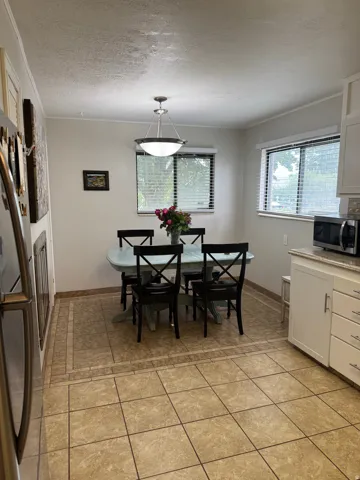 Tile flooring with decorative border, white cabinetry, light-colored countertops, and a modern ceiling light fixture