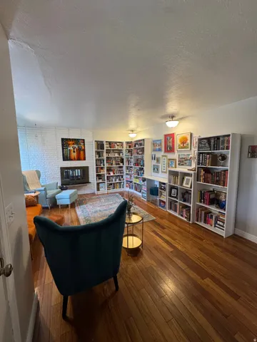Hardwood flooring, white brick fireplace, built-in shelving, white ceilings, and flush-mount lighting