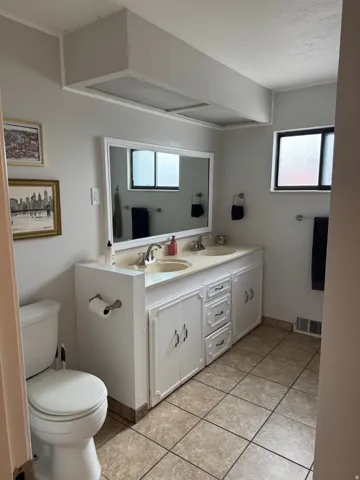 Dual vanity with integrated sinks, white cabinetry, and a framed mirror