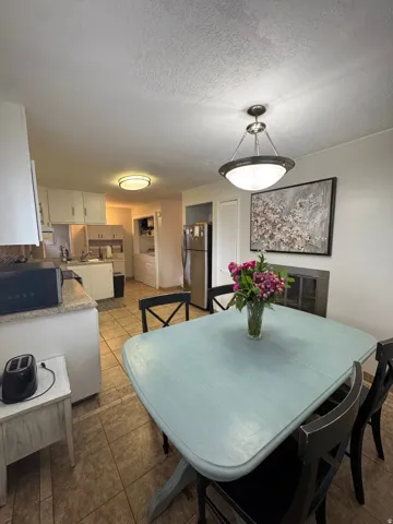 Kitchen and dining area featuring tile flooring, white cabinetry, and stainless steel appliances
